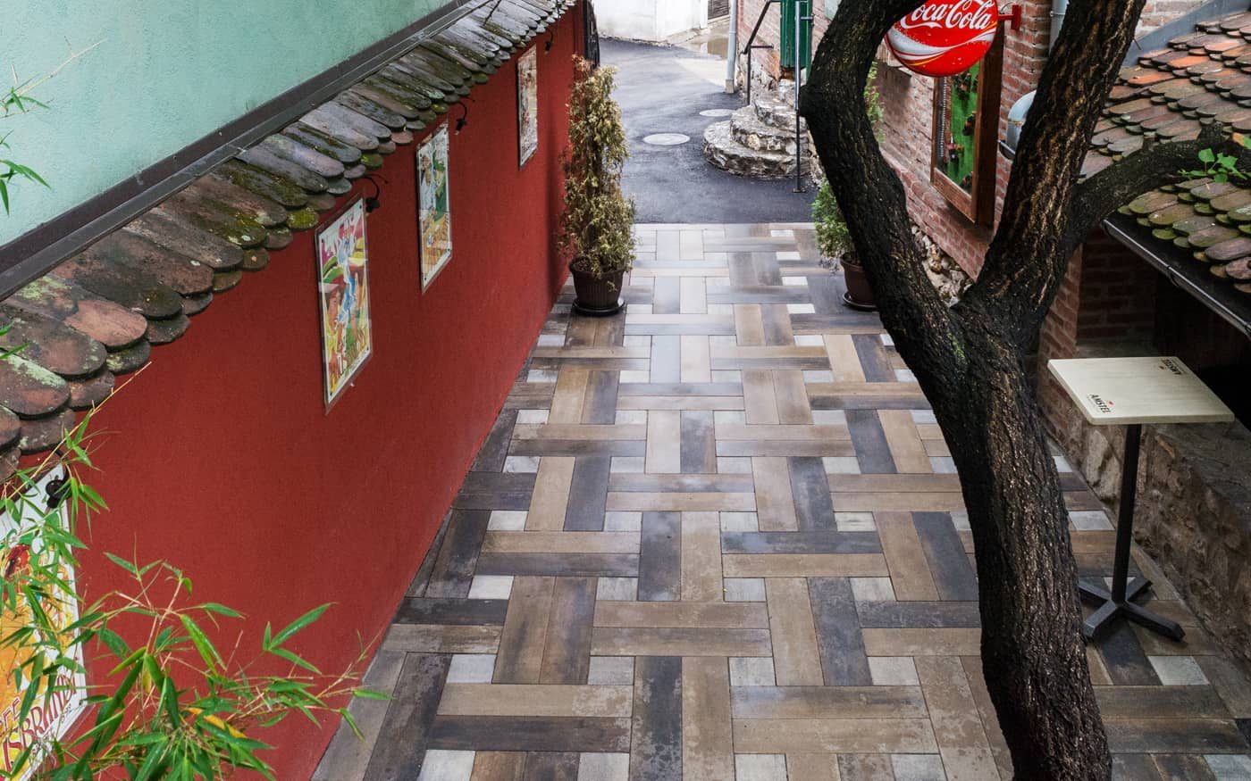 Uski prolaz uz crveni zid popločan izduženim behaton pločama u ukrasnom slogu, model Ambient Line