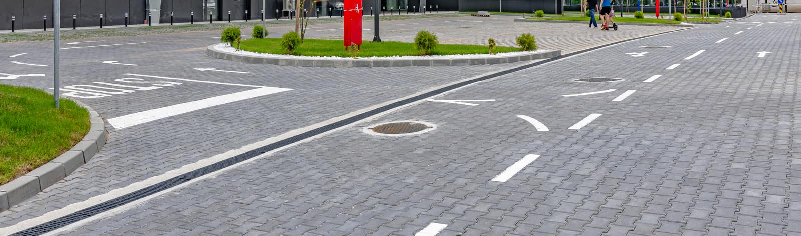 Kolovoz sa saobraćajnim oznakama i zelenim ostrvom popločan sivim behaton pločama, model Duplo T