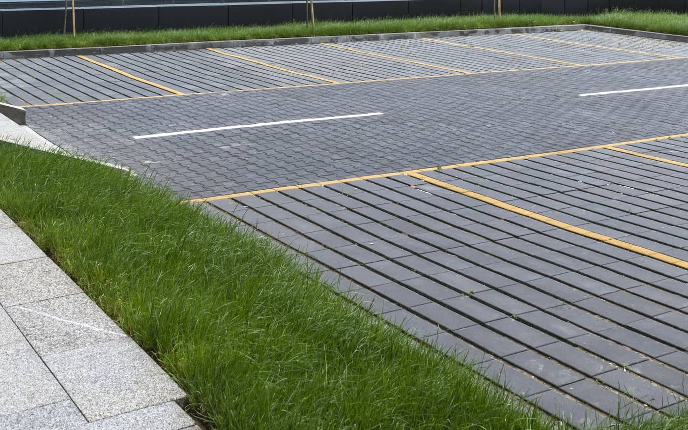 Parkiralište sa žutim obeležavanjem popločano tamno sivim pločama sa razmakom za travu, model Domino Grass