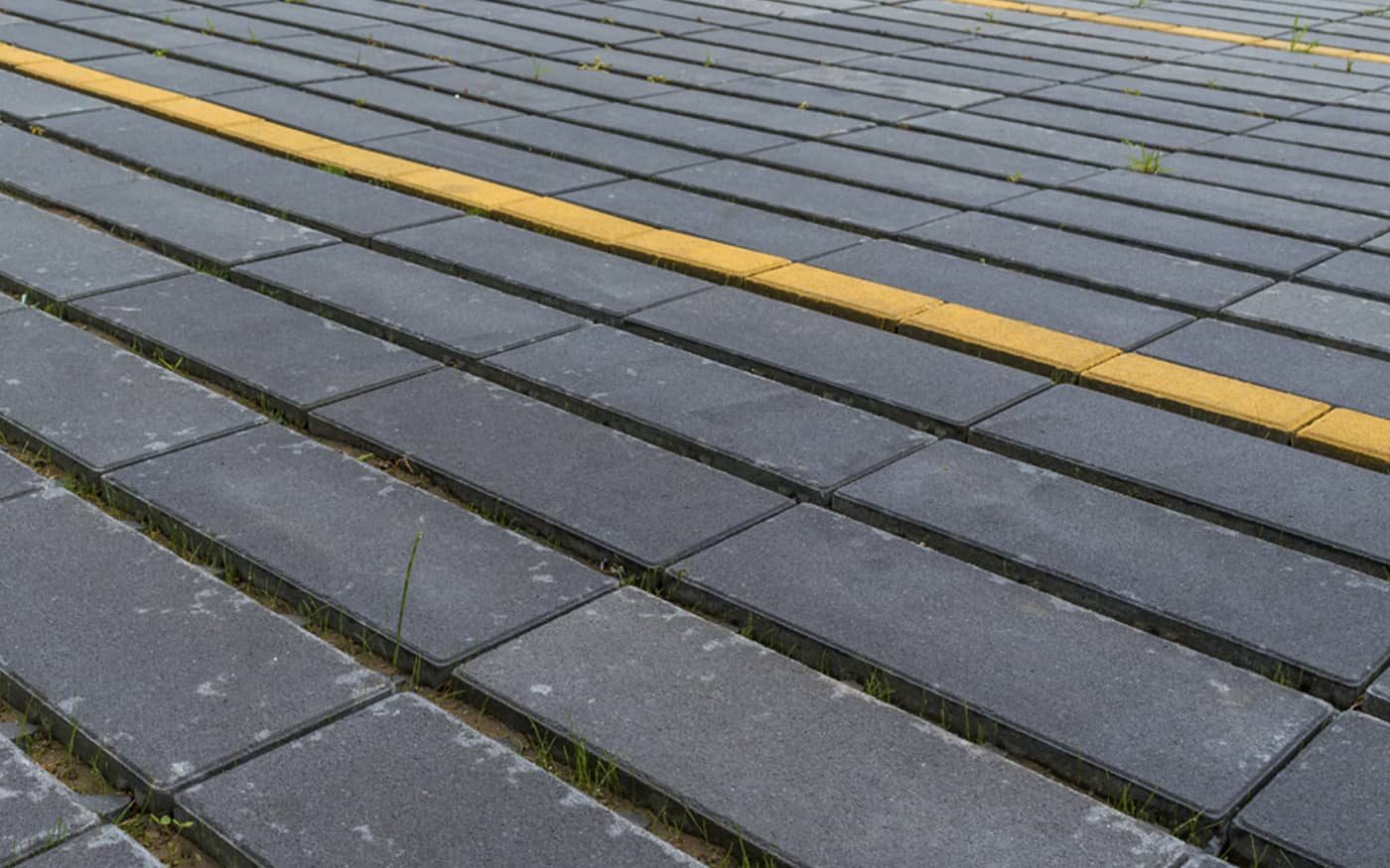 Tamno sive ploče sa travnatim fugama i žutom linijom parking mesta, izbliza, model Domino Grass
