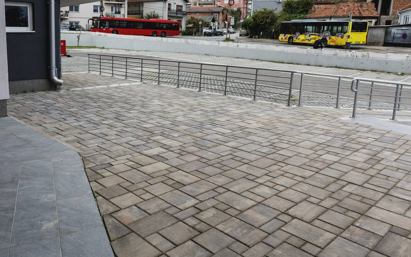 Plato uz zgradu sa ogradom popločan behaton pločama u više formata, sivo-braon, model Kombo