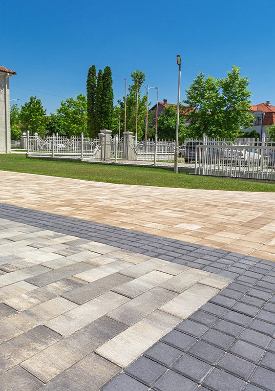 Plato uz travnjak popločan izduženim behaton pločama u sivim i bež tonovima sa tamnom bordurom, model Modena
